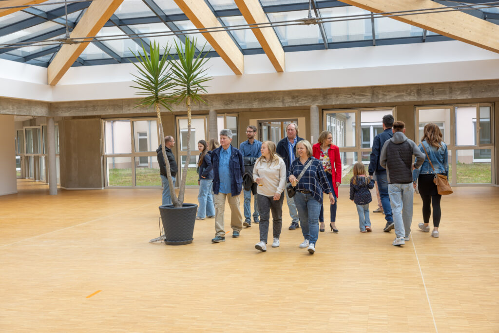 Besucher:innen auf dem Weg durch das Atrium der Nachsorgeklinik am Straussee