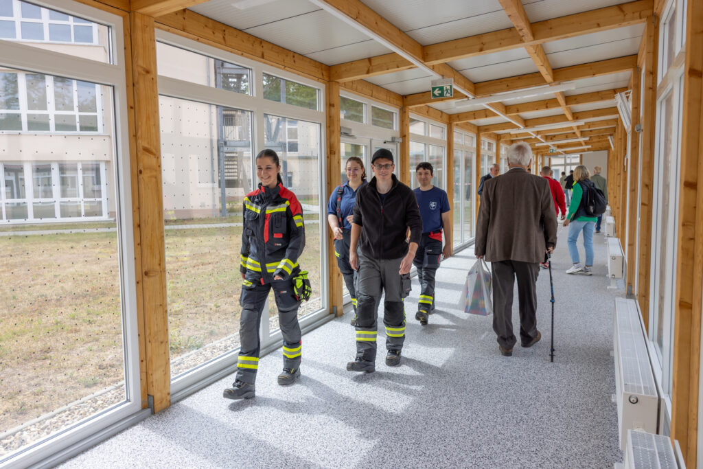 Besucher:innen auf dem Weg durch einen der Laubengänge der Nachsorgeklinik am Straussee