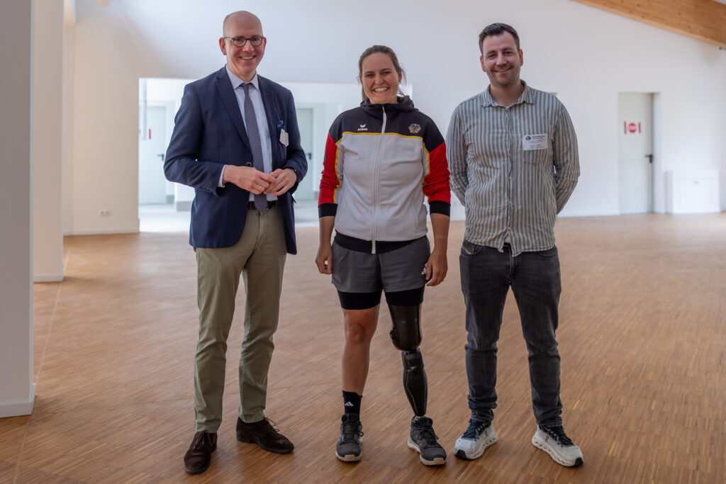 Geschäftsführer Jan Dreher mit Flora Kliem, Paralympics-Teilnehmerin im Bogenschießen, und Marco Jäger, Mitarbeiter der Nachsorgeklinik am Straussee